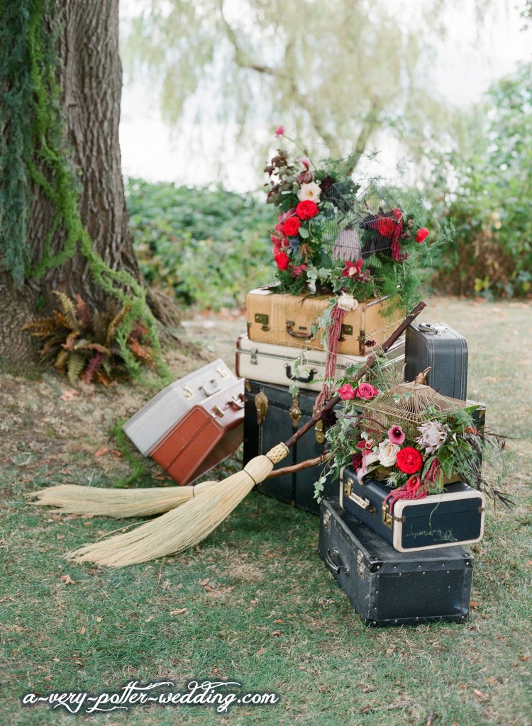 A stack of suitcases and birdcages with flowers and broomsticks